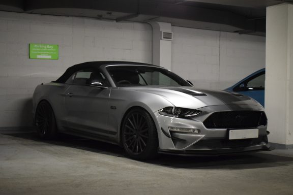 Silver convertible sports car parked in a garage.