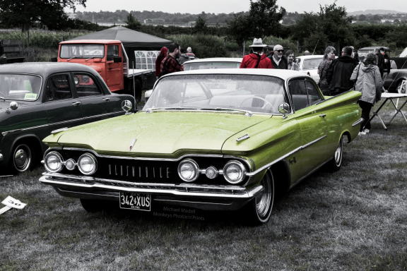Bright green vintage car parked among other vehicles at an outdoor event.