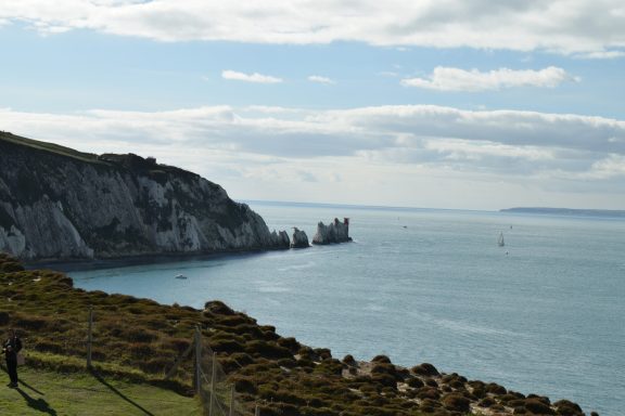 Coastal view with cliffs, calm sea, and a cloudy sky.